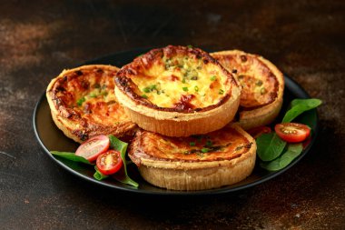 Çedar peyniri ve taze soğanlı omlet turtaları yanında salatayla birlikte siyah tabak servis ediliyordu. Sağlıklı kahvaltı.