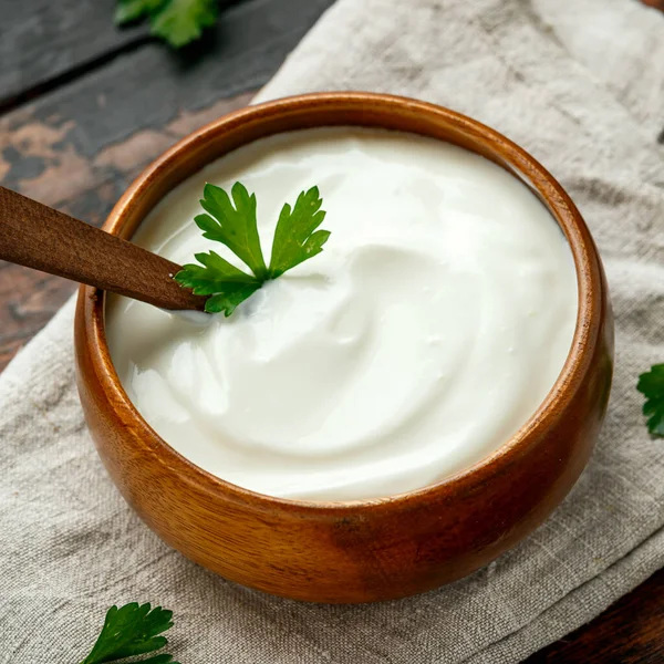 Greek yogurt in bowl on rustic wooden table