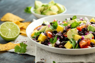 Avokado, siyah fasulyeli mango salatası, domates, kırmızı soğan ve tortilla cipsi. sağlıklı yiyecekler
