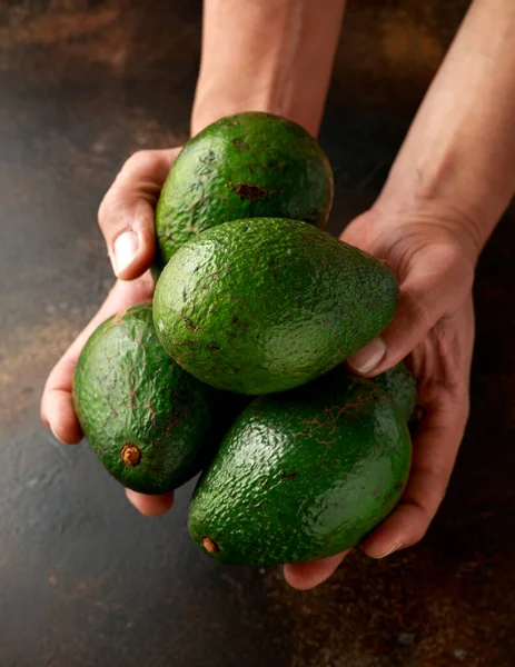 Свежий органический зеленый авокадо в руках человека — стоковое фото
