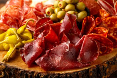 Kurumuş mayalanmış et ve domuz eti karışımı. Salam, sucuk, peynir, zeytin ve üzümle ahşap tahtada servis ediliyor.