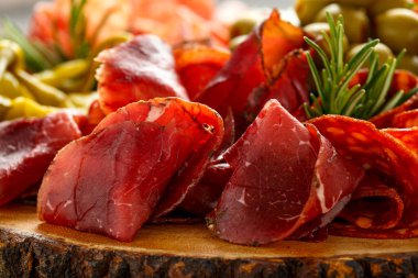 Kurumuş mayalanmış et ve domuz eti karışımı. Salam, sucuk, peynir, zeytin ve üzümle ahşap tahtada servis ediliyor.