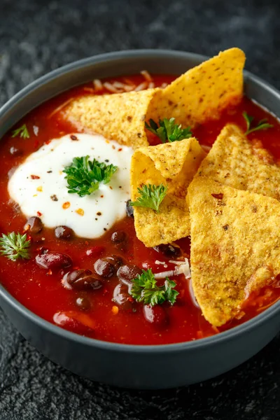 Мексиканський суп з йогуртом, сиром і чіпси з тортільї в чорній мисці. — стокове фото