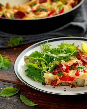 Siyah beyaz tabakta salatalı Chorizo Frittata. sağlıklı sabah kahvaltısı.