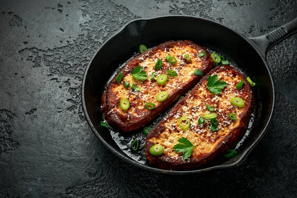 Queso parmesano tostada francesa con cebolla primaveral en sartén de hierro fundido — Foto de Stock