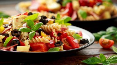 Makarna, domates, zeytin, kırmızı soğan, dolma biber, salam, peynir, enginar ve fesleğen ile Antipasto salatası..