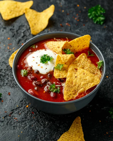 Мексиканський суп з йогуртом, сиром і чіпси з тортільї в чорній мисці. — стокове фото