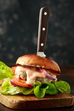 Tahtada bıçakla servis edilen lezzetli ördek etli hamburger.