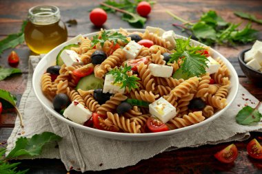 Domatesli makarna salatası, siyah zeytin, salatalık ve beyaz tabakta beyaz peynir. sağlıklı yiyecekler.