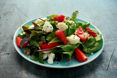 Keçi peyniri ve çilekli yaz salatası nigella ve susam tohumlarıyla servis edilir.