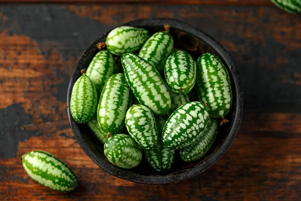 Cucamelon appena colto in ciotola rustica sul tavolo di legno — Foto Stock