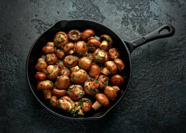 Demir tavada soğanlı ve sarımsaklı kızarmış mantar.