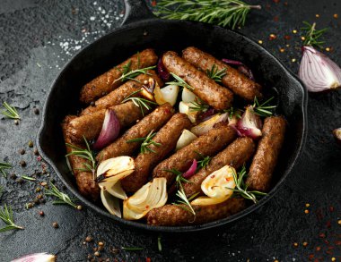 Biberiye ve soğanlı vejetaryen sosis fırını dökme demir tavada kızartılıyor.
