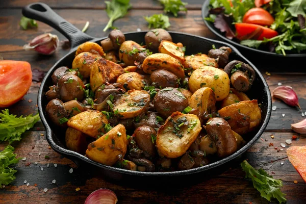 Запеченный картофель с грибами и травами в чугунной сковороде на деревянном столе — стоковое фото