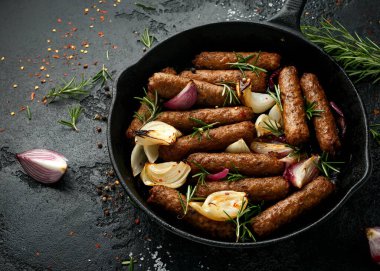 Biberiye ve soğanlı vejetaryen sosis fırını dökme demir tavada kızartılıyor..