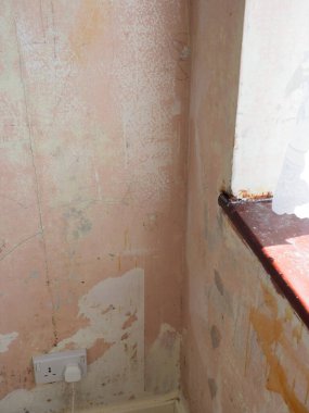 Çıplak duvarları ve yamalı alçıyı gösteren bir oda.