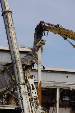 Modern bir çelik yapı bir makine tarafından yıkılıyor.