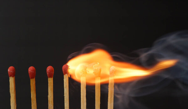 row of burning matches with smoke isolated on black background