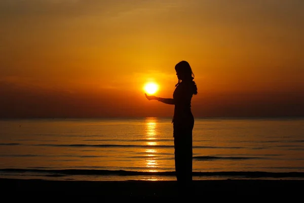 silhouette of female holding sun on the beach