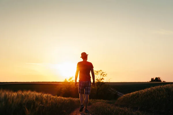 Νεαρός Άνδρας Περπάτημα Στο Λασπωμένο Δρόμο Στο Ηλιοβασίλεμα — Φωτογραφία Αρχείου