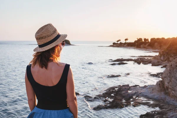 Günbatımı üzerinde bir uçurumun bir sahil, genç kadının