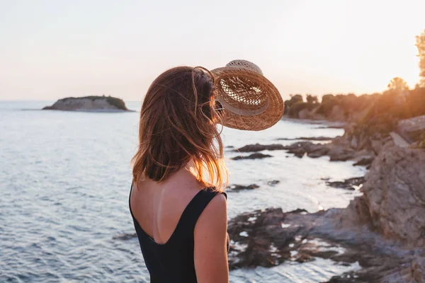 Günbatımı üzerinde bir uçurumun bir sahil, genç kadının