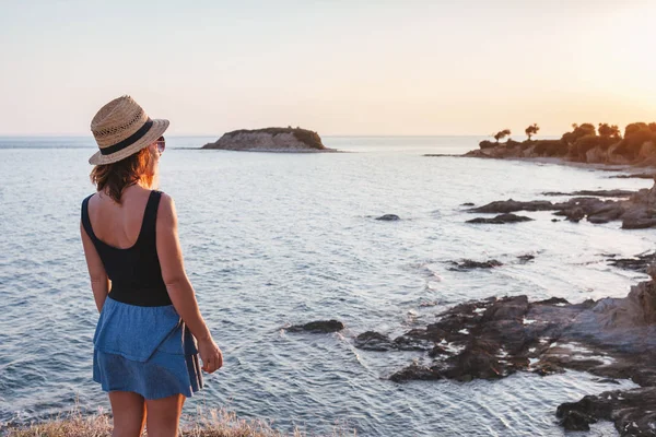 Günbatımı üzerinde bir uçurumun bir sahil, genç kadının