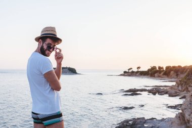 Genç adam günbatımı bir uçurumun bir sahil, zevk