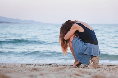 Yalnız ve depresyonda sahilde oturan kadın
