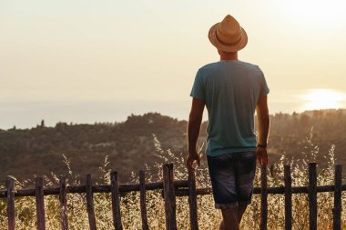 Genç adam deniz kenarında günbatımının tadını çıkarıyor.