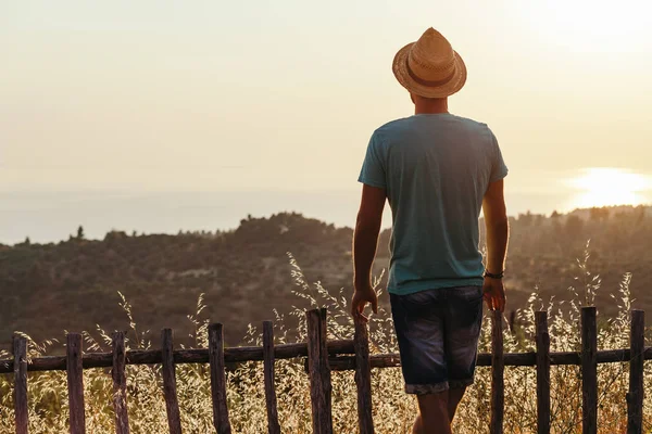 Genç adam deniz kenarında günbatımının tadını çıkarıyor.