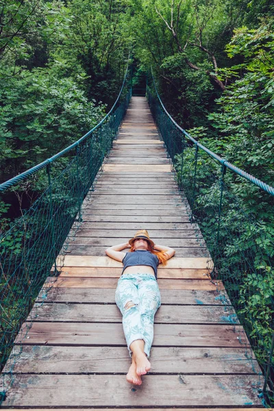 夏を楽しんでいる木製の橋の上に横たわる森林の若い女性 — ストック写真
