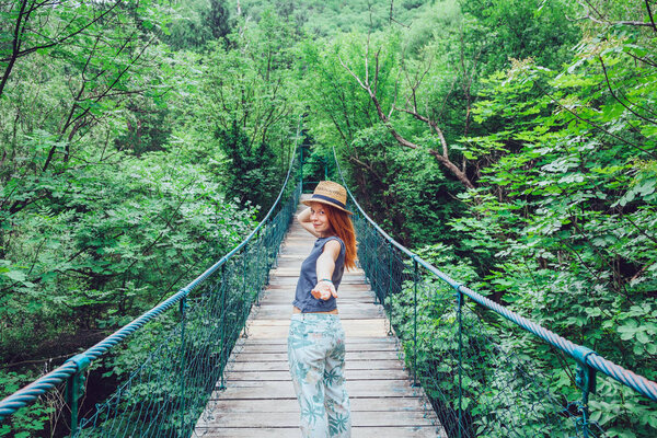 Young woman holding hand on the bridge, leading to adventure 