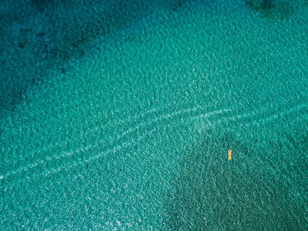 Aerial view of woman floating on the water mattress in the turquoise sea