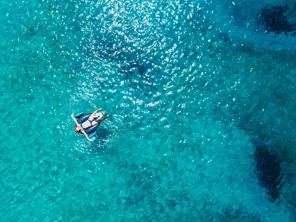 Aerial view of woman floating on the water mattress in the turquoise sea