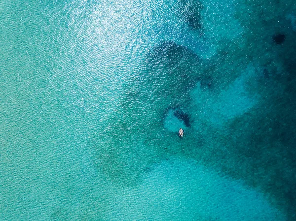 Aerial view of woman floating on the water mattress in the turquoise sea