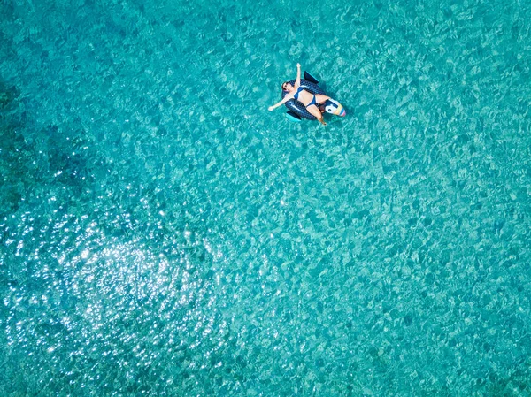 Aerial view of woman floating on the water mattress in the turquoise sea