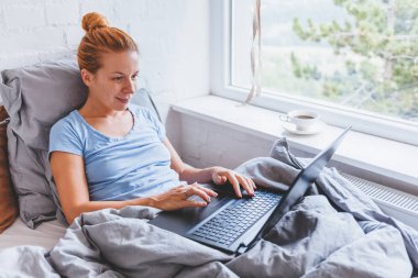 Sabah erkenden yatakta dizüstü bilgisayarda çalışan kadın