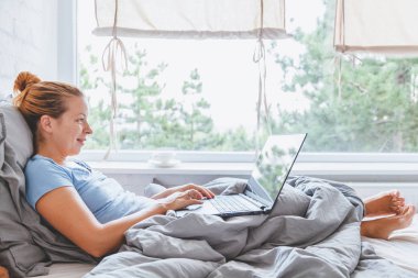 Sabah erkenden yatakta dizüstü bilgisayarda çalışan kadın