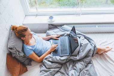 Sabah erkenden yatakta dizüstü bilgisayarda çalışan kadın