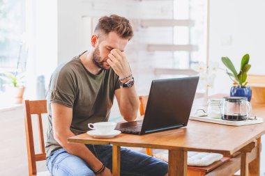 Genç adam üstünde Laptop çalışma sressful vakit geçiriyor