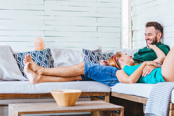 Young couple enjoying their time, laughing on couch in their home