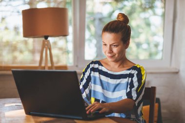 Ev ofis içinde laptop üzerinde çalışan genç kadın