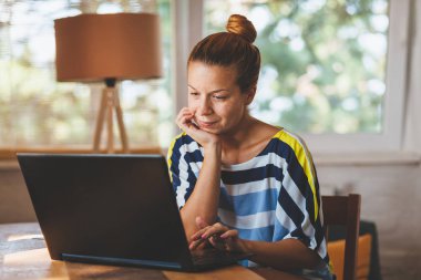 Ev ofis içinde laptop üzerinde çalışan genç kadın