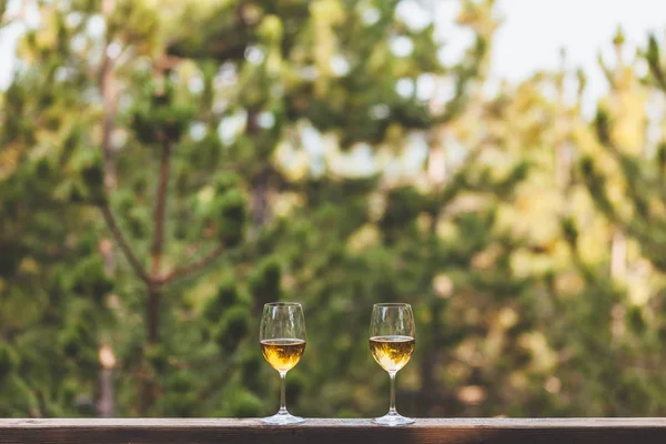 Two glasses of white wine on the balcony with a view on the mountain forest