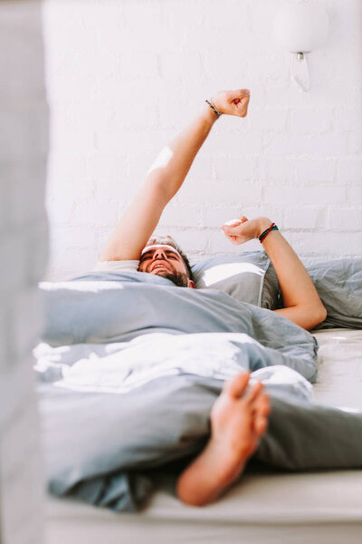 Young man waking up in the bed in the morning