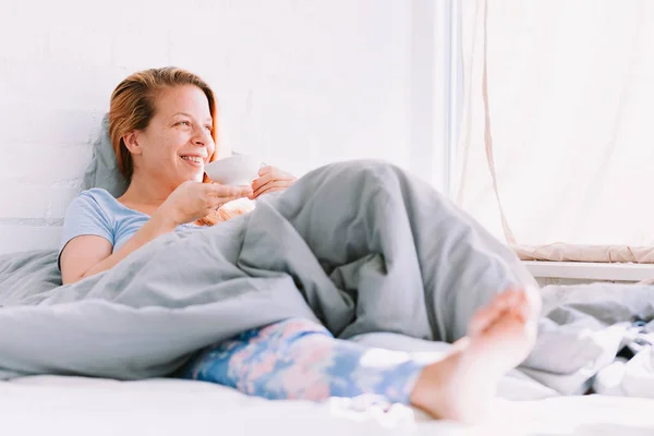 Young woman drinking coffee in bed