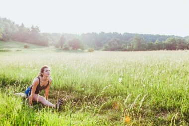Genç kadının günbatımında doğa egzersiz yapması