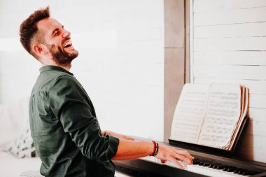 Young man playing electric piano at home clipart