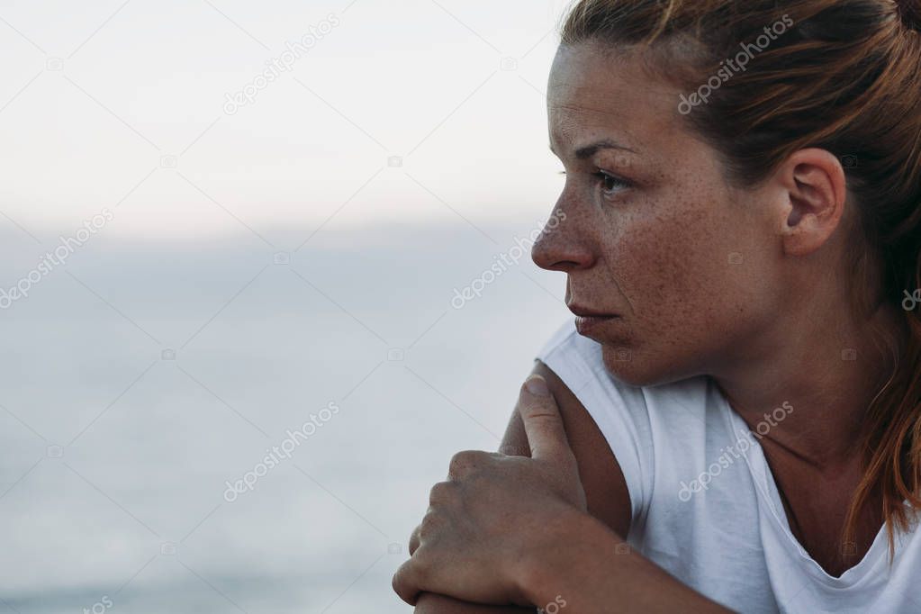 Young woman feeling sad by the sea